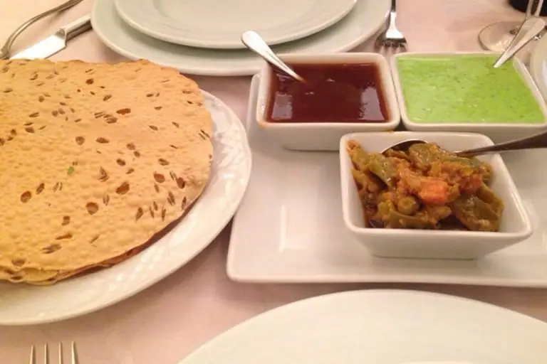 Papadums on a plate with tamarind and mint chutneys and a small dish of vegetable curry