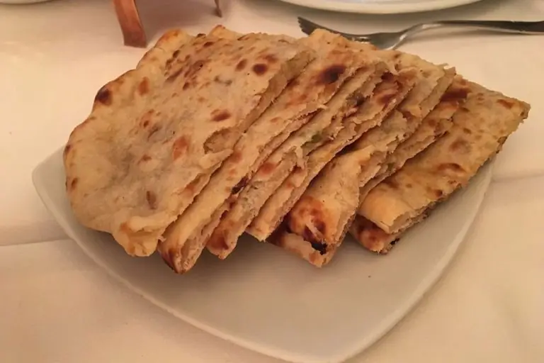 Plate of stuffed naan or paratha bread cut into wedges
