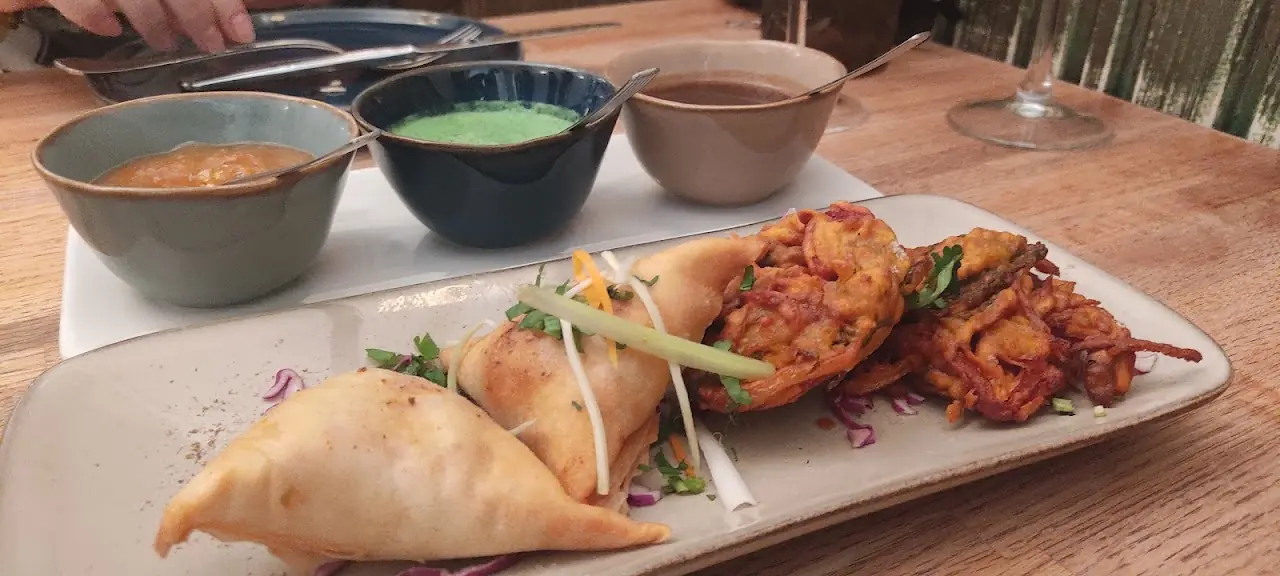 Fried appetizers arranged on a platter with three small dipping sauces on the side.