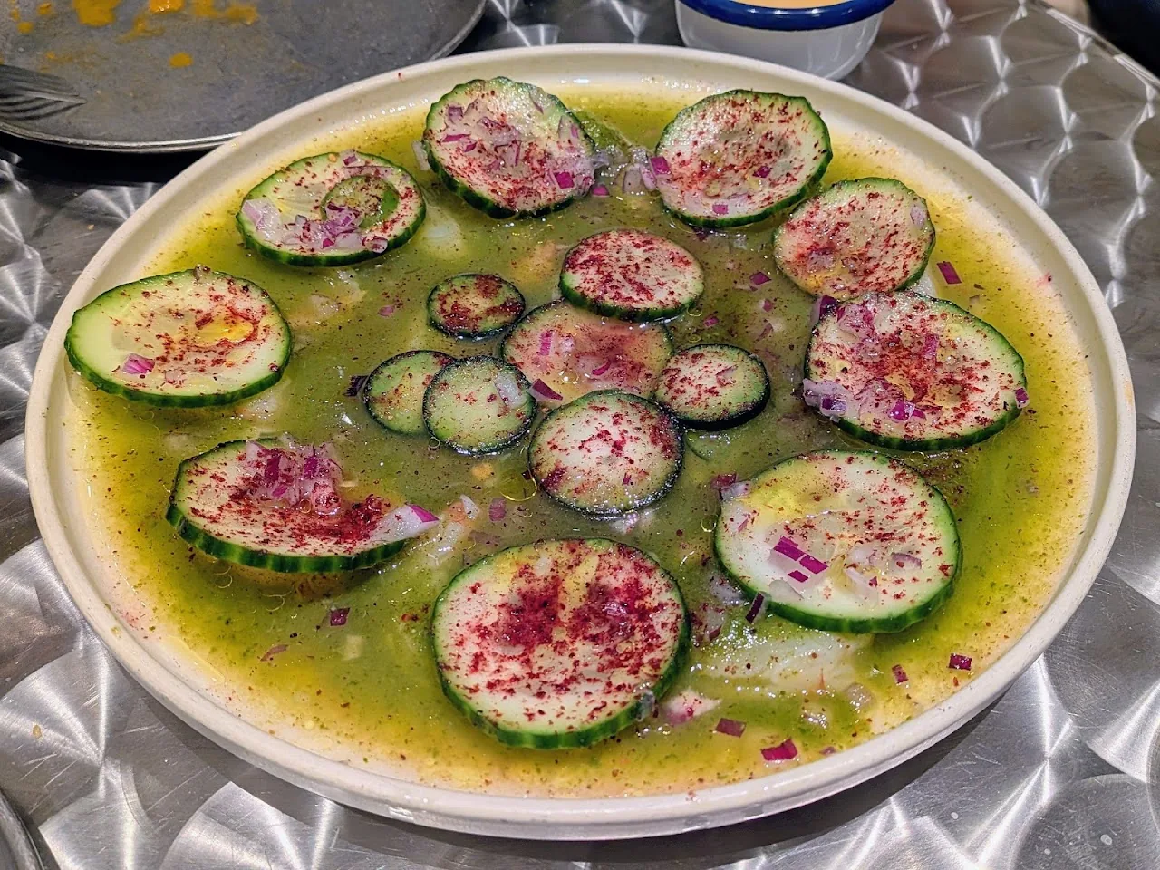 A plate of sliced cucumber and radish in a citrus marinade