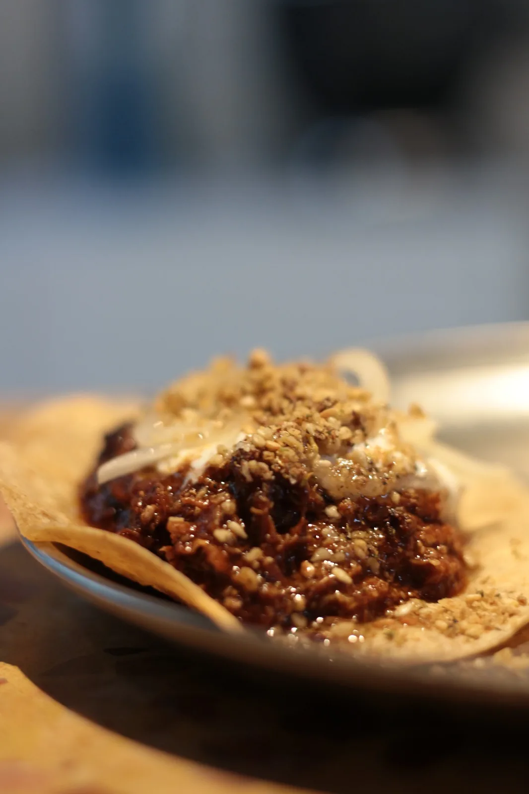 A tostada topped with braised meat and crushed peanuts