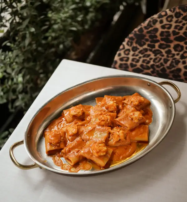 Rigatoni pasta with prawns in a tomato sauce, served in a metal dish, Isabella's