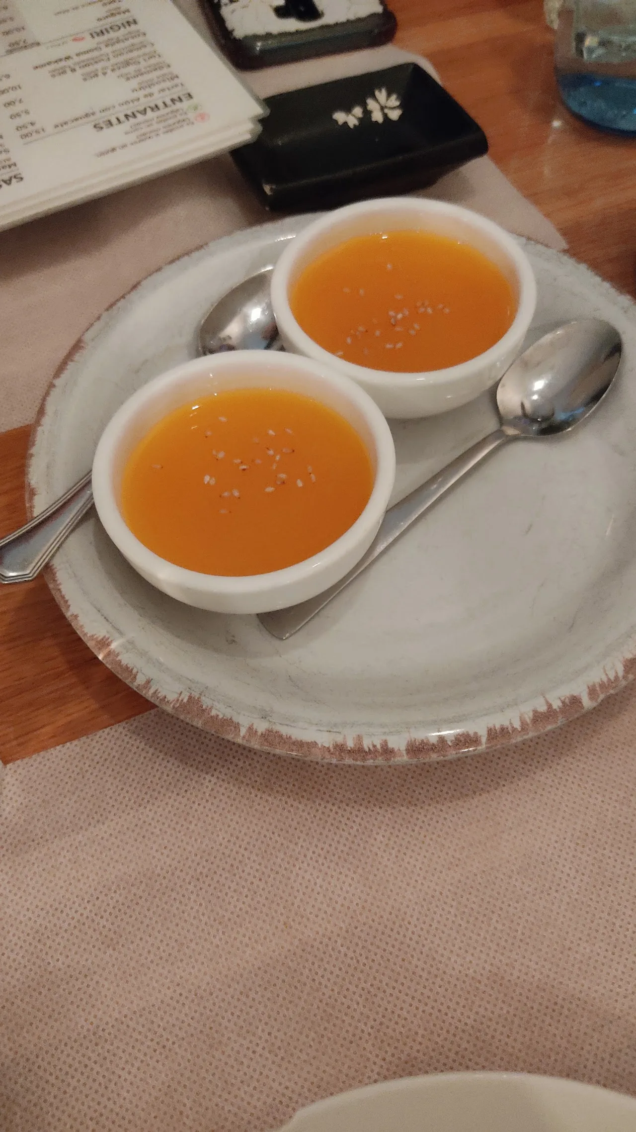 Two cups of orange soup on a saucer