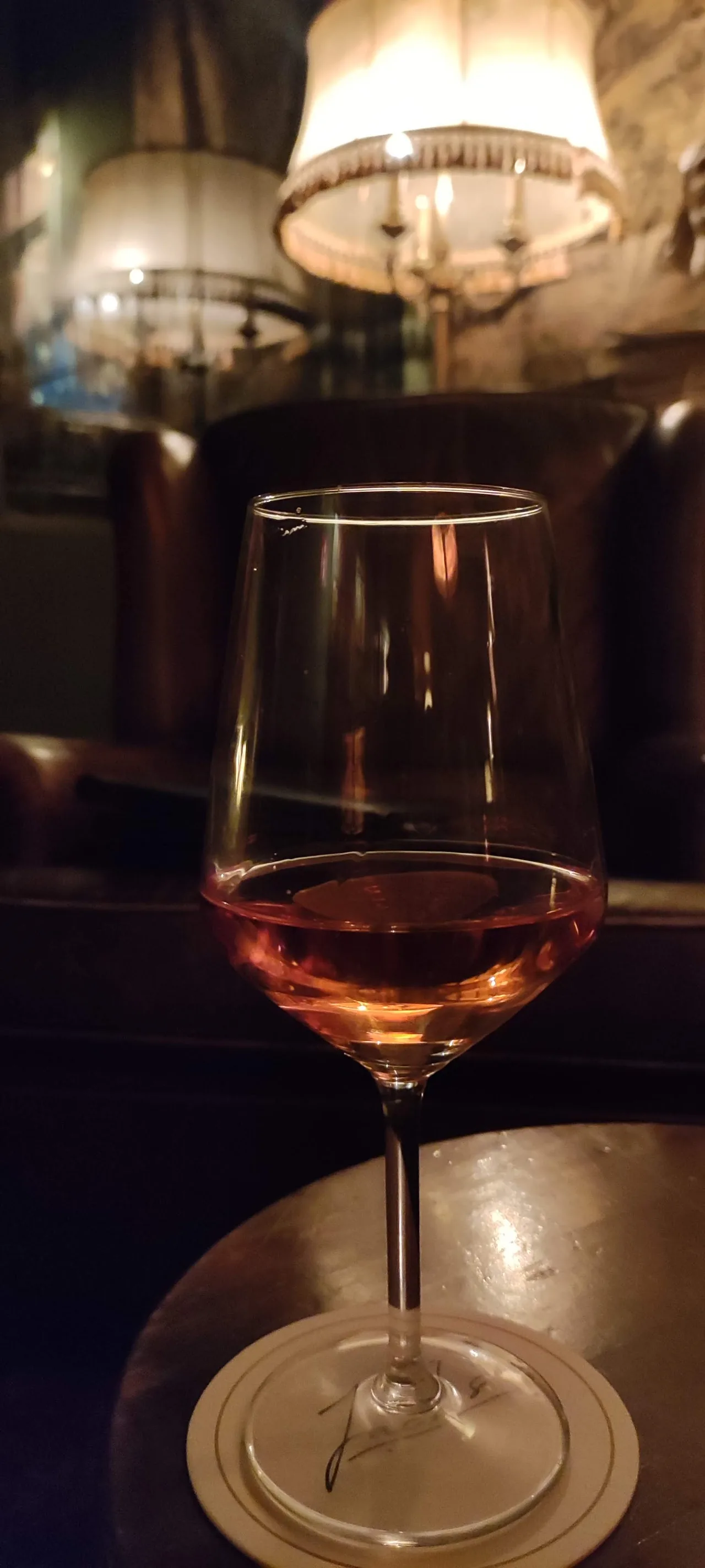 A glass of rosé wine on a dark table