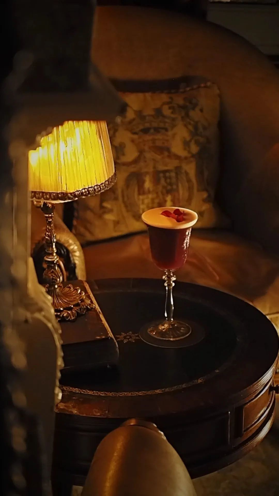 A red cocktail in a coupe glass on a side table