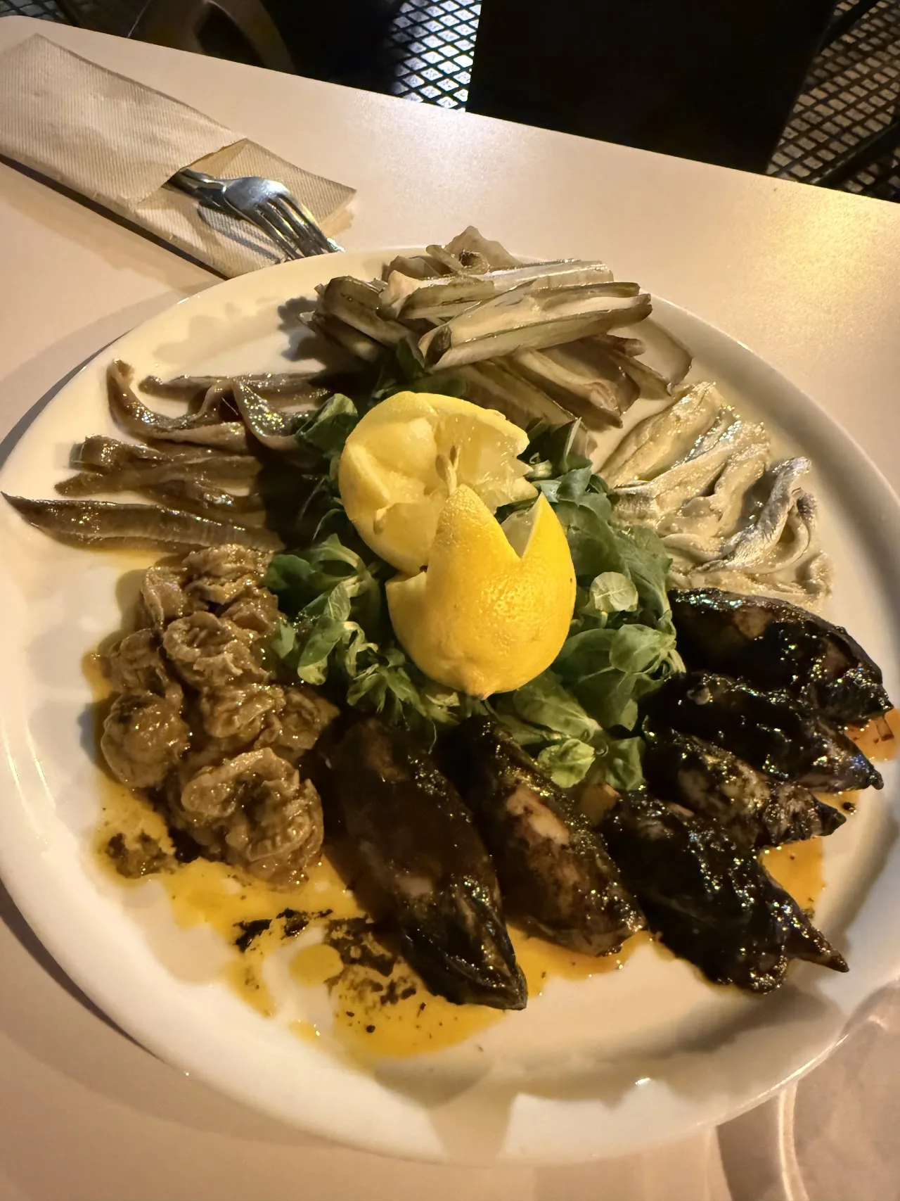 A plate of grilled vegetables and mushrooms with a lemon wedge