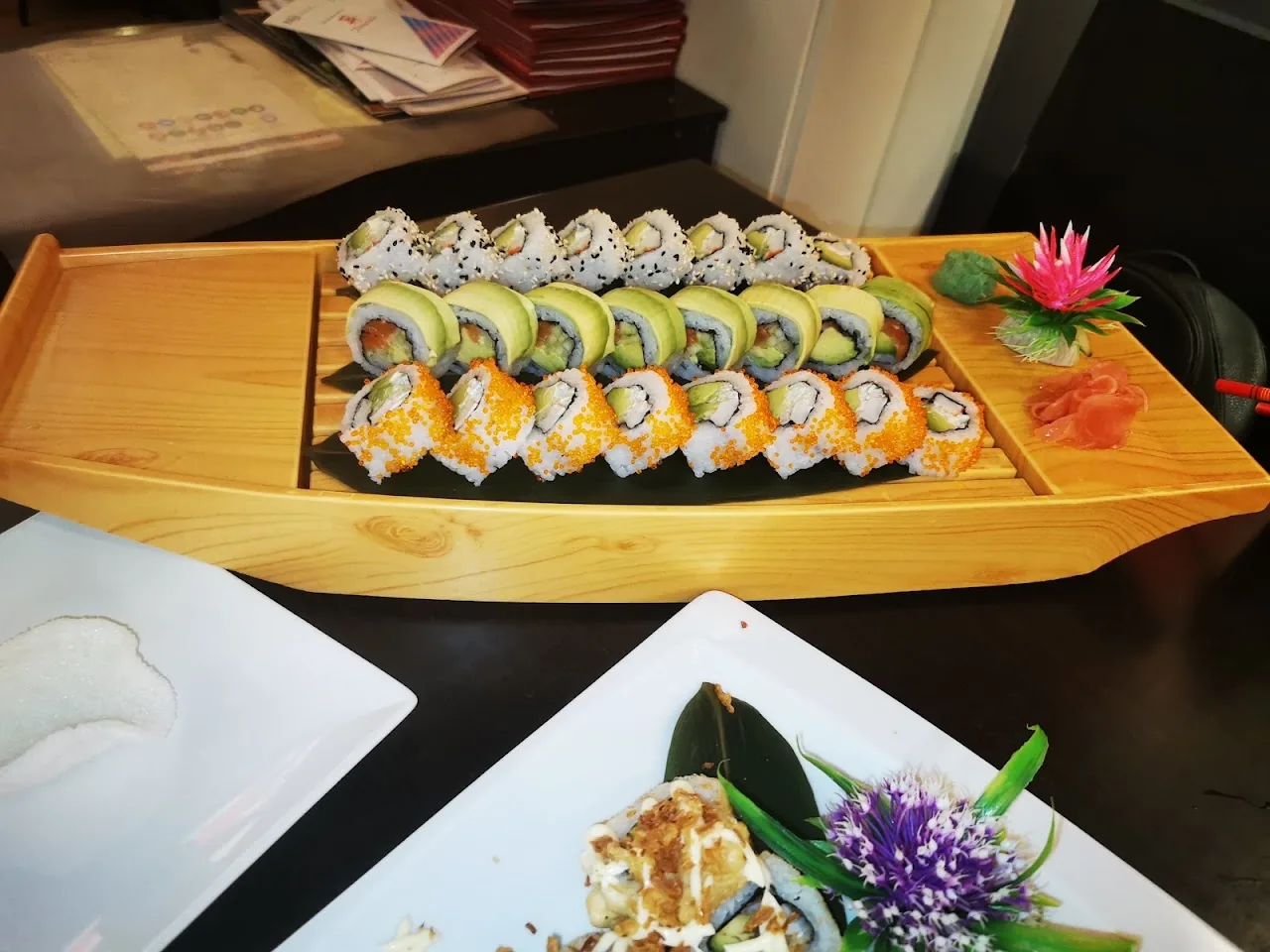 A wooden boat platter of sushi rolls