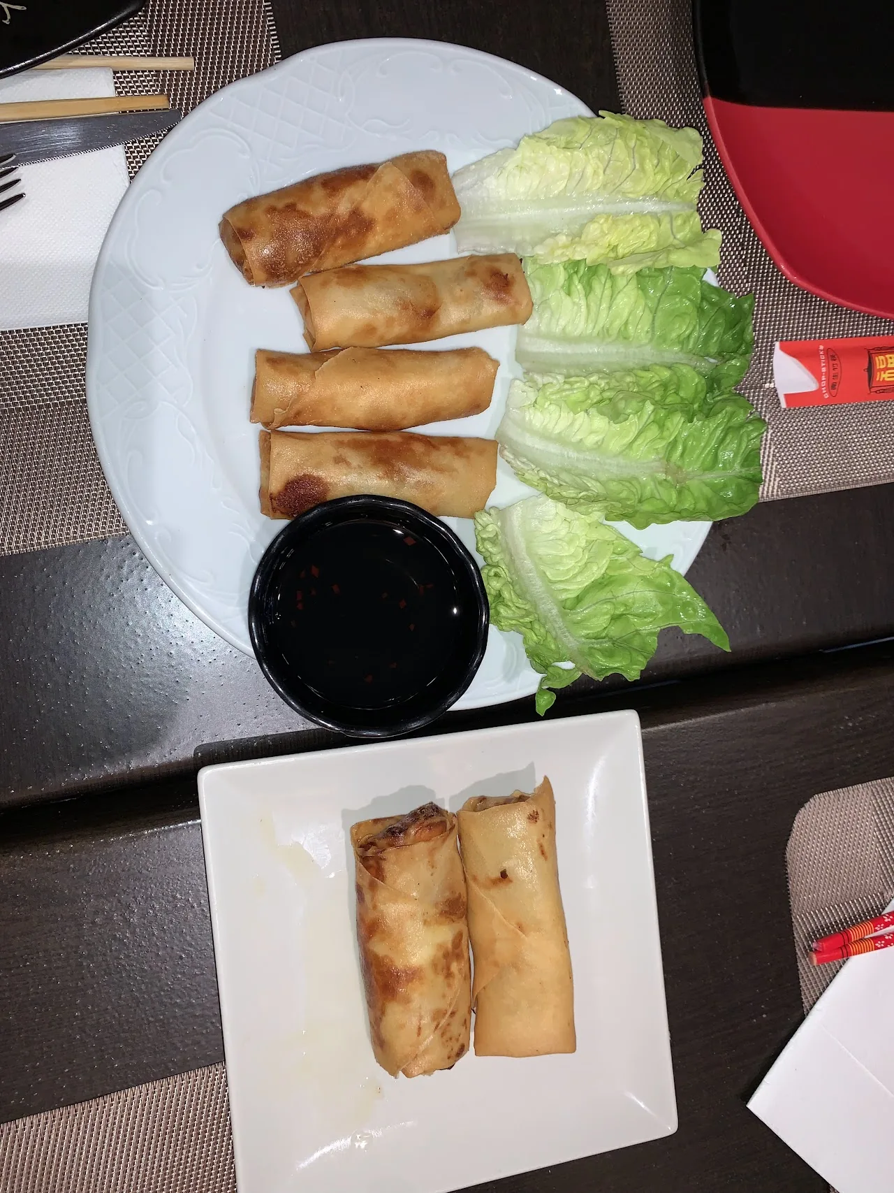 A plate of spring rolls with lettuce wraps and dipping sauce