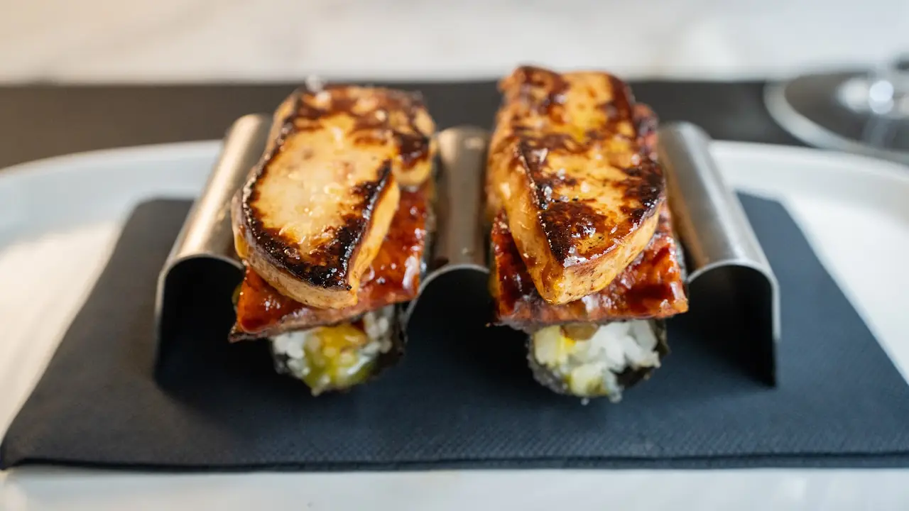Two open-faced tostas topped with seared foie gras, served upright in a metal holder
