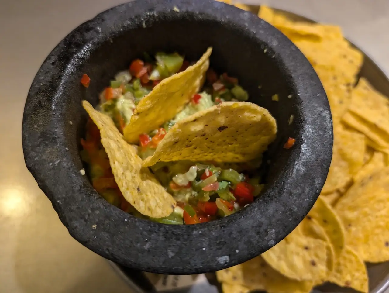 Tortilla chips and salsa served in a stone molcajete.