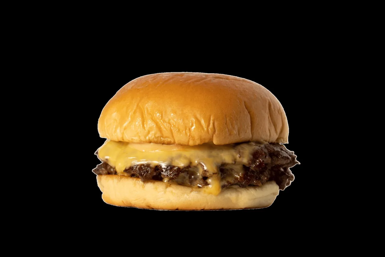 A smash burger with melted cheese on a glossy bun against a black background