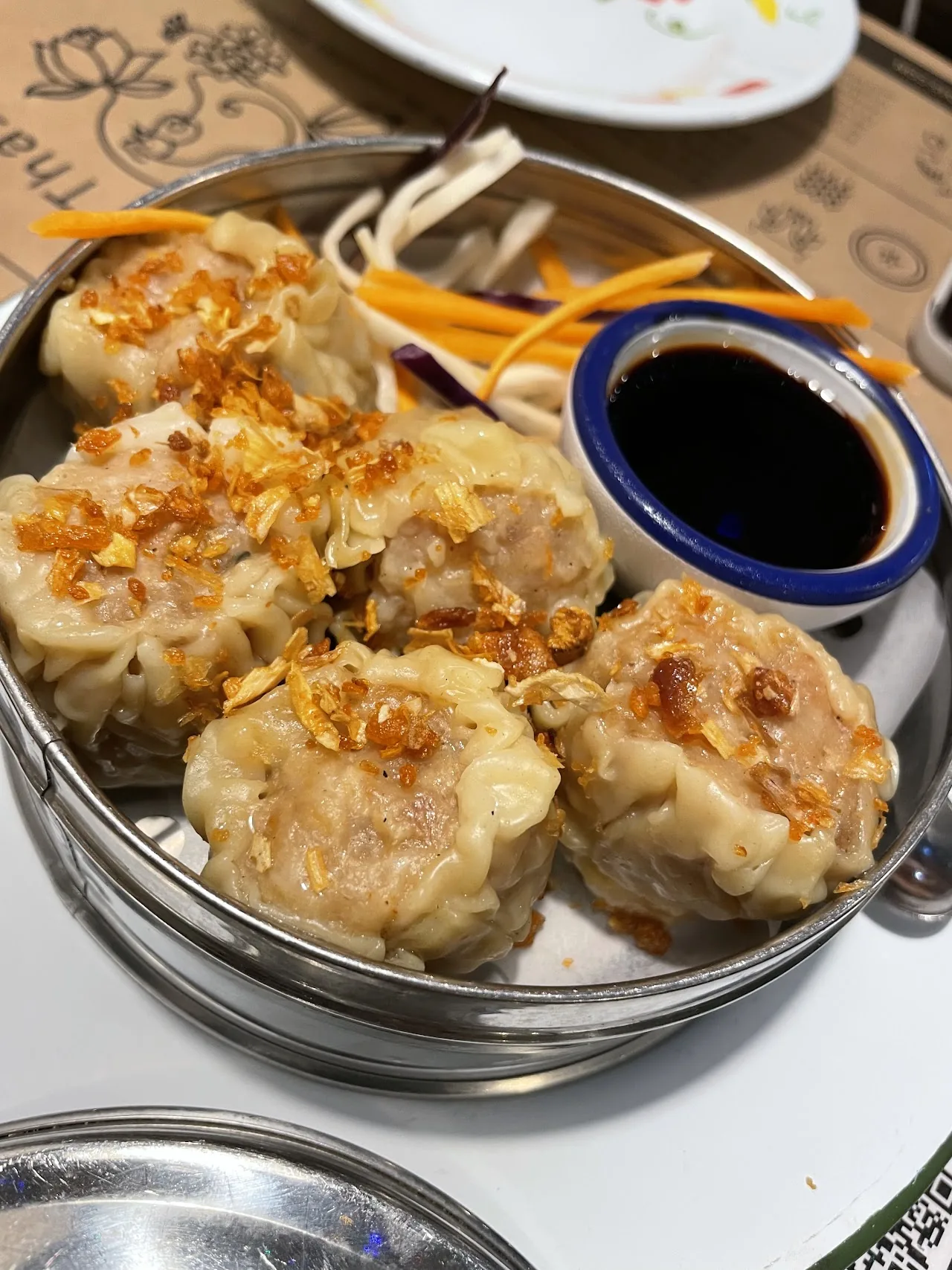 A steamer basket of fried dumplings with soy dipping sauce