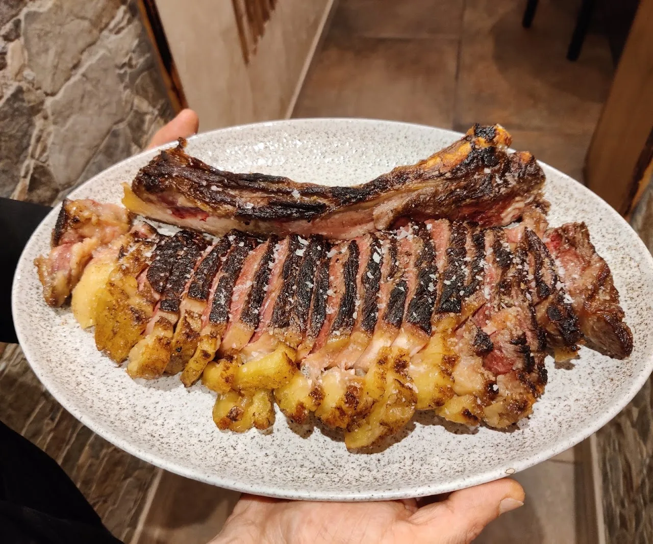 A whole rack of grilled ribs with charred potatoes on a plate