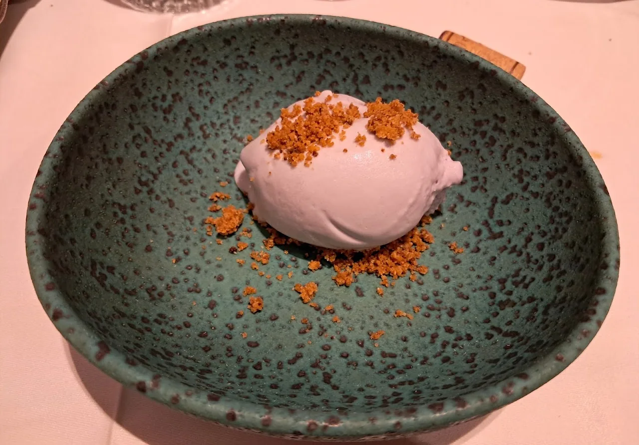 A scoop of pink sorbet with crumble in a teal bowl