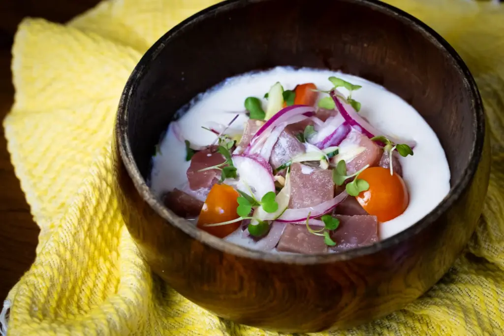 Diced raw fish ceviche in coconut milk with red onion, cherry tomato, and microgreens, served in a dark wooden bowl, Kasarap Filipino Kitchen
