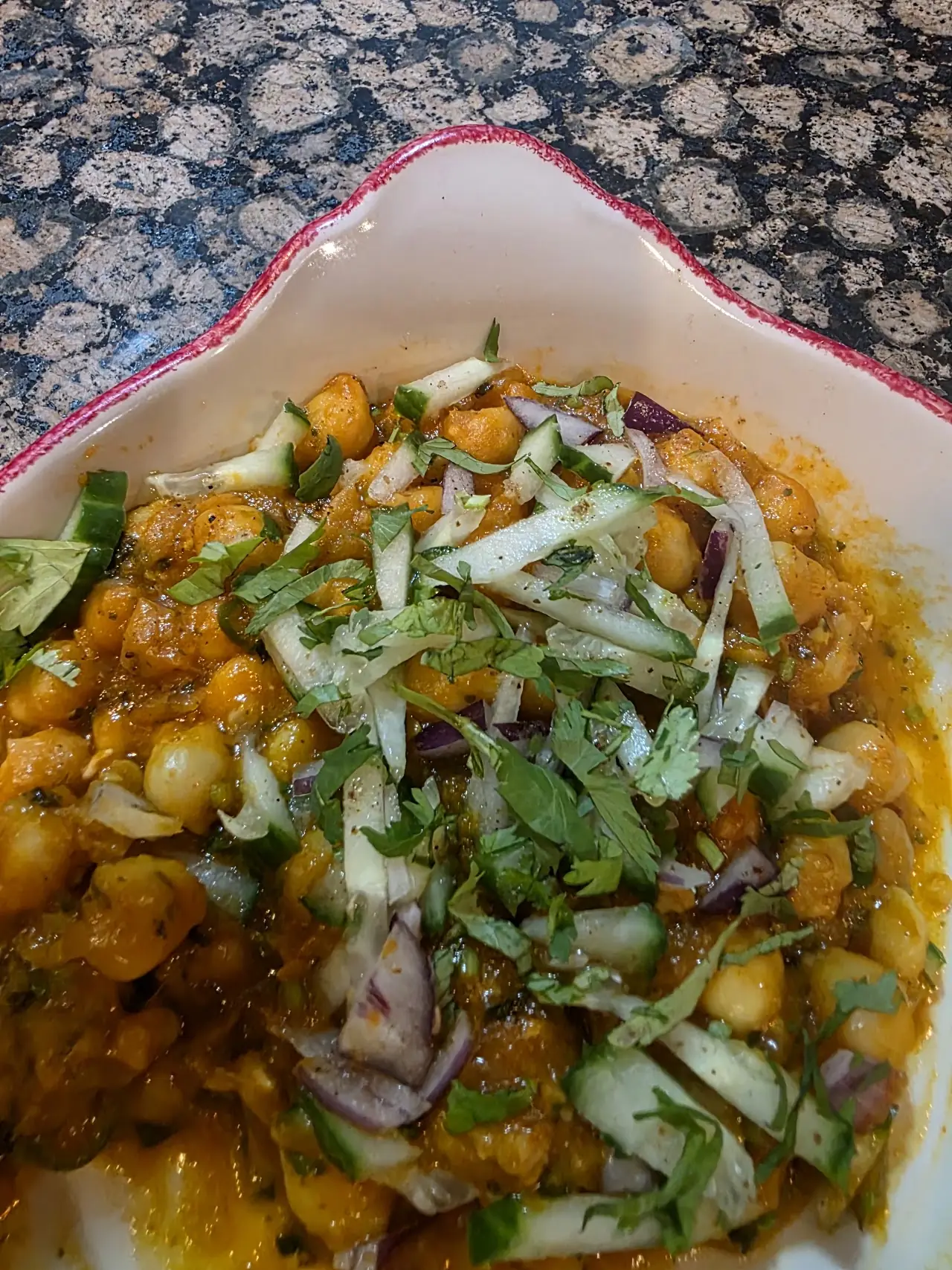 Chickpea curry topped with sliced onion and fresh coriander in a bowl.