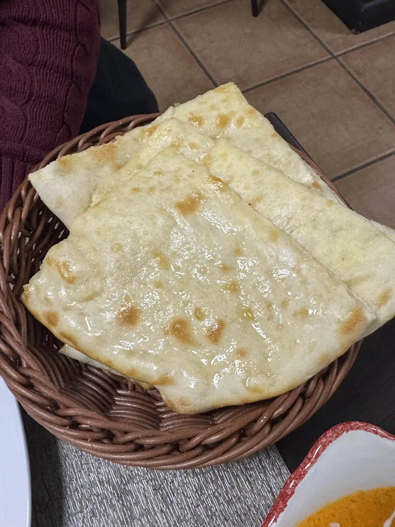 Warm naan bread folded in a woven basket.