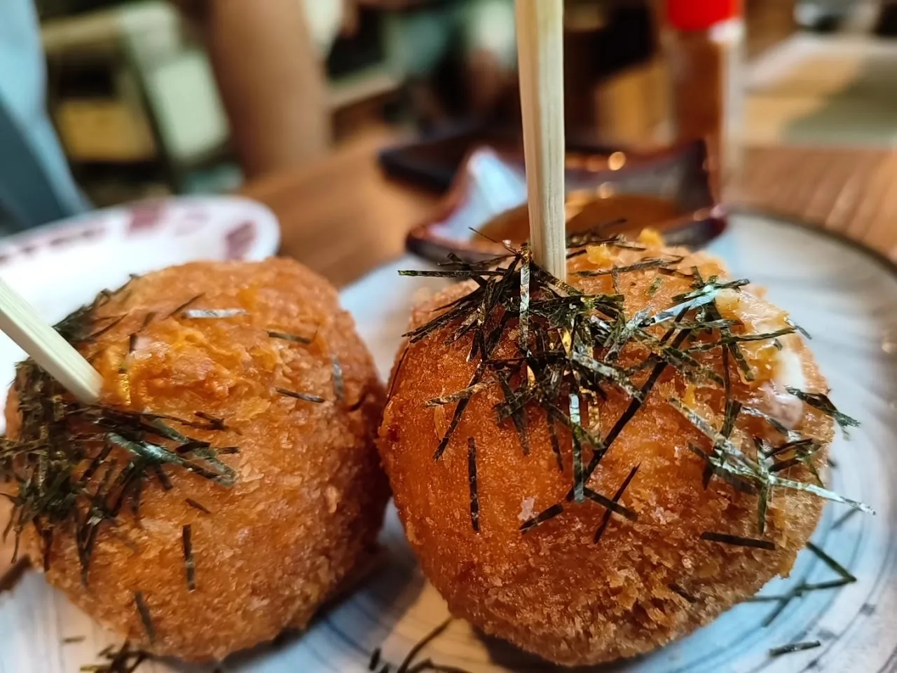 Two crispy takoyaki balls topped with bonito flakes