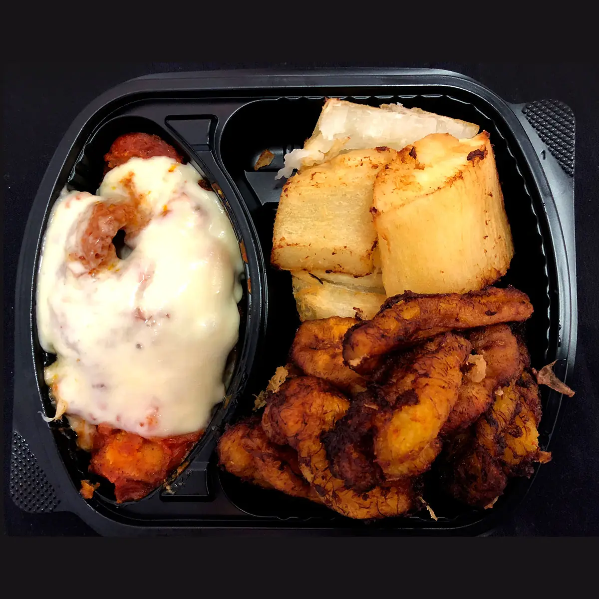 Combination takeaway plate with cheese-topped meat in tomato sauce, fried yuca, and fried plantain slices, at K'Delicia Restaurant Brasileño