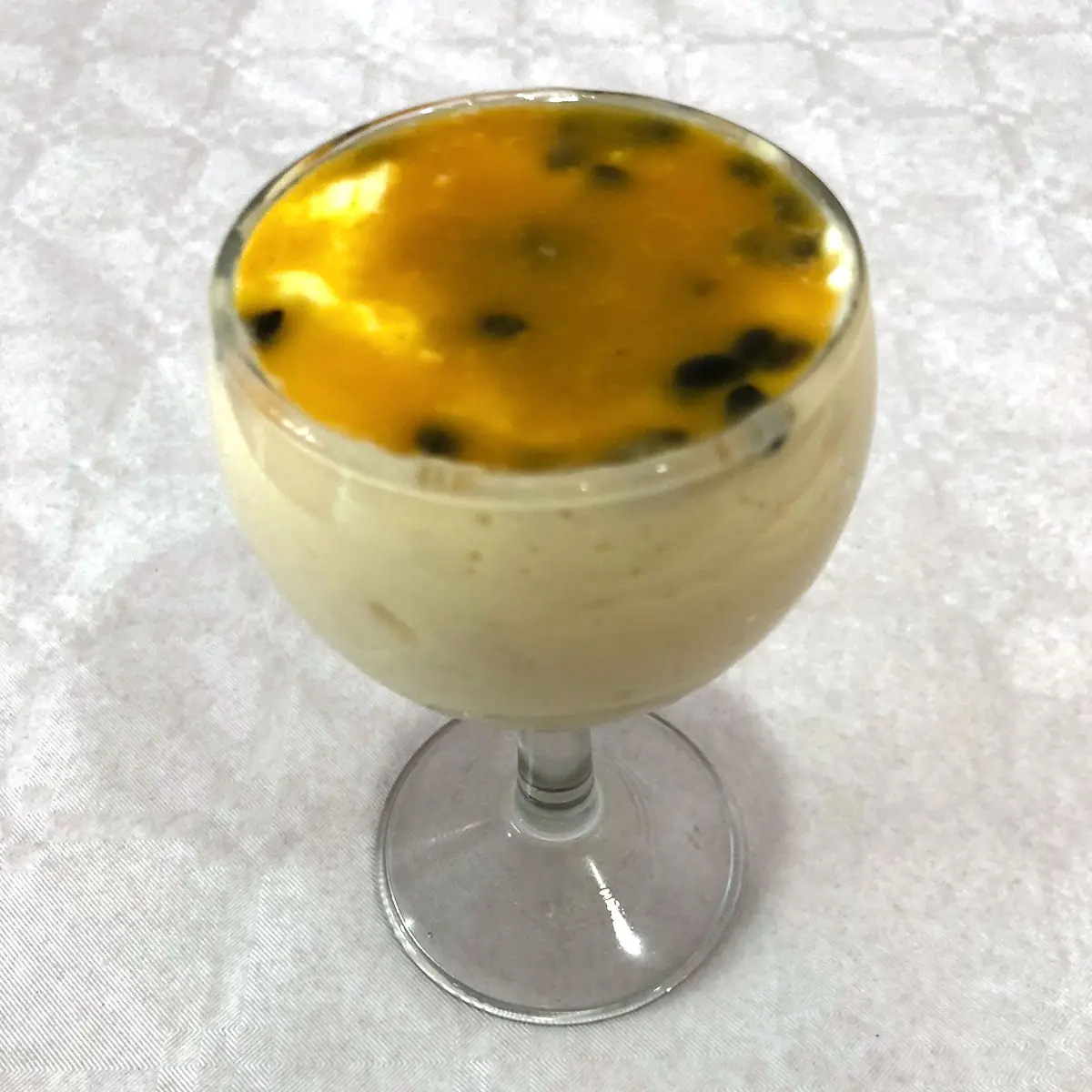 Passion fruit mousse in a stemmed glass, topped with passion fruit pulp and seeds, at K'Delicia Restaurant Brasileño