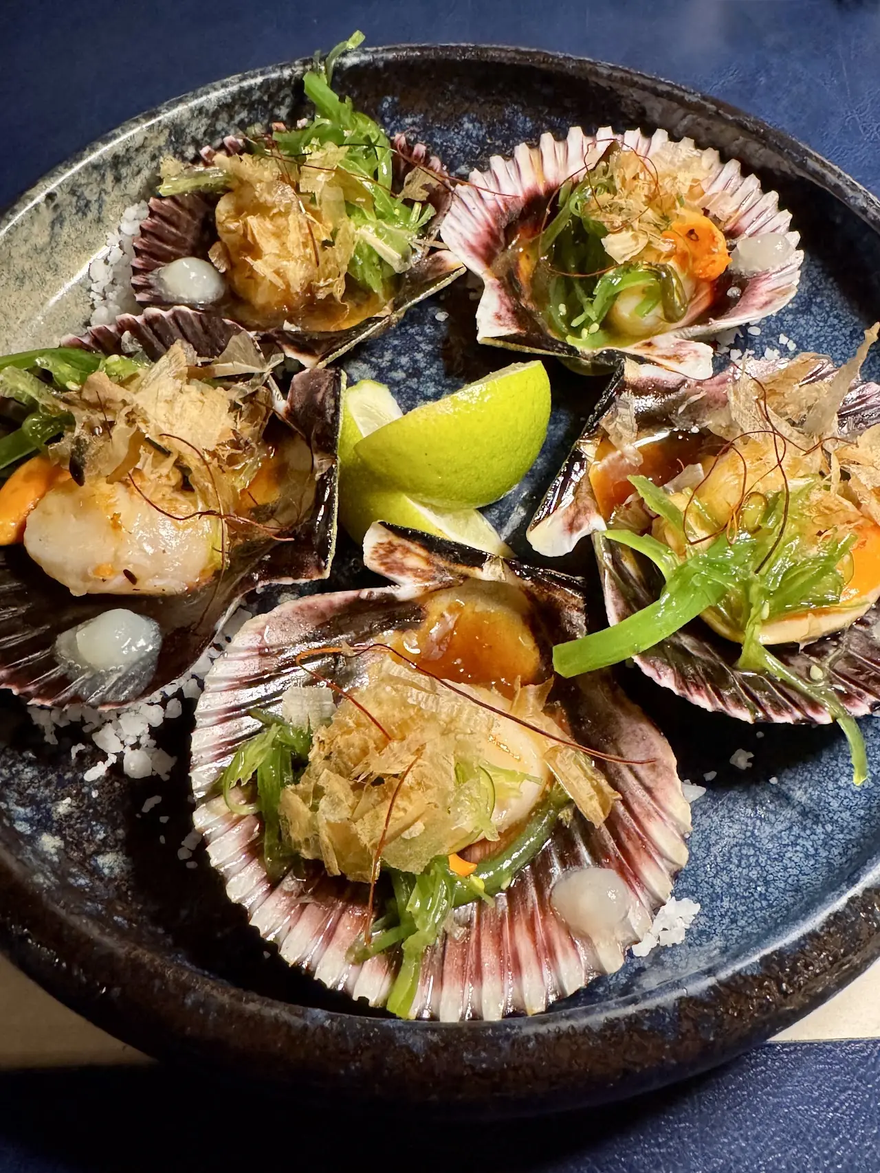 Seared scallops on the half shell with a lime wedge and micro greens