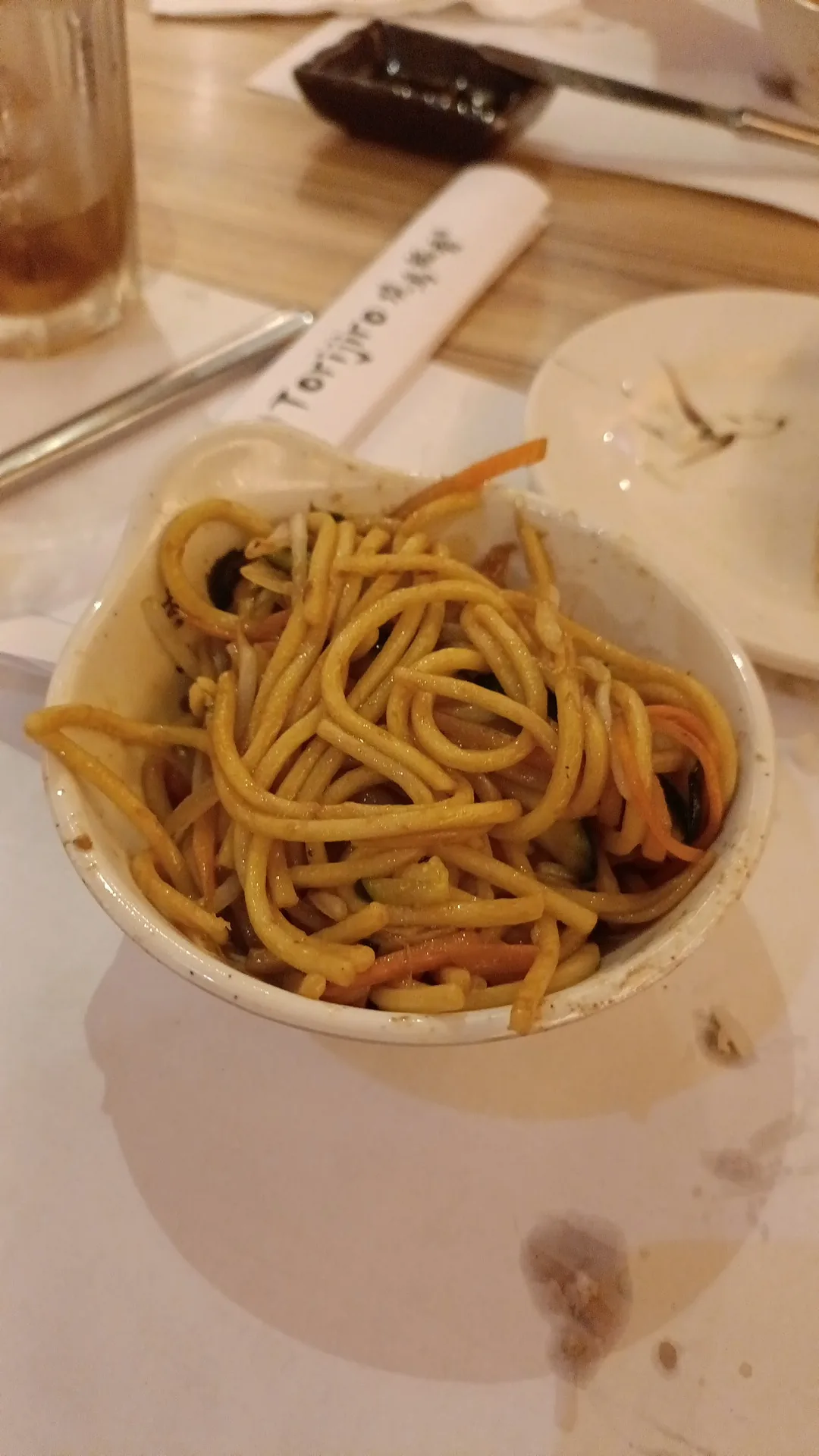 A white bowl of stir-fried teriyaki noodles with vegetables
