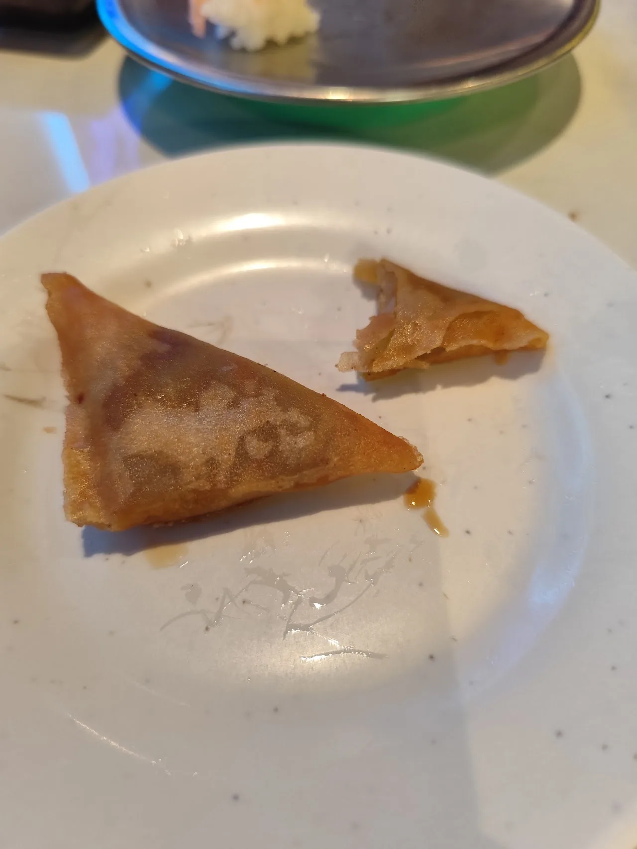 A partially eaten fried pastry on a white plate