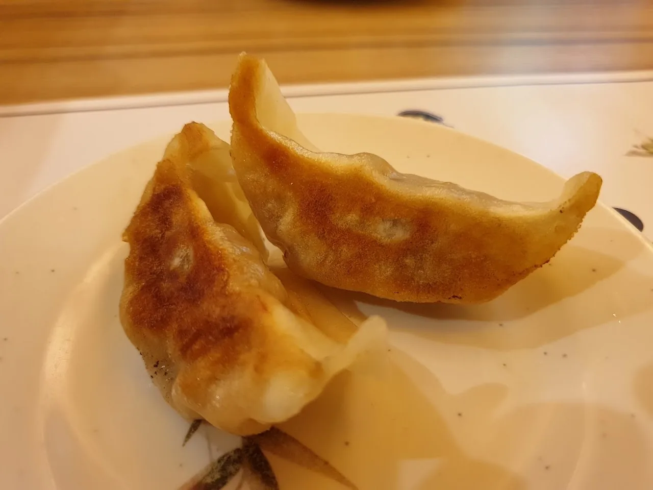 Three golden pan-fried dumplings on a white plate