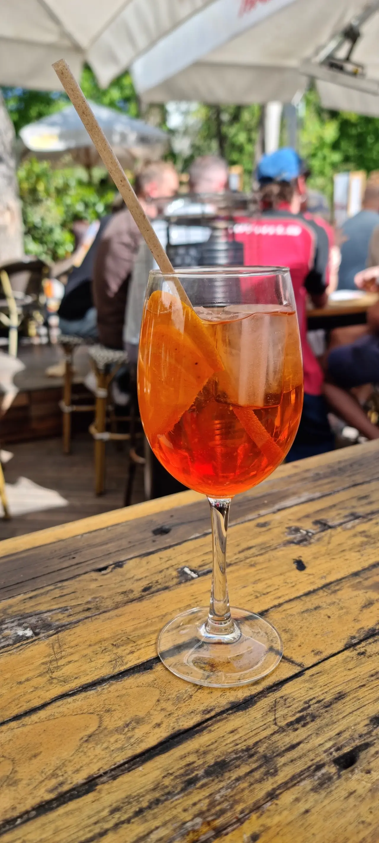 Orange spritz cocktail with orange slices and ice on a wooden outdoor table