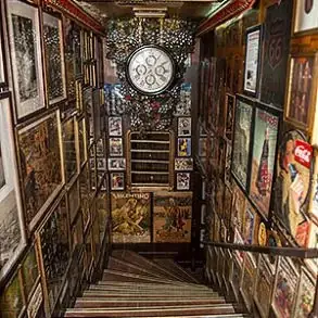 Narrow staircase inside the pub lined floor to ceiling with vintage posters and memorabilia