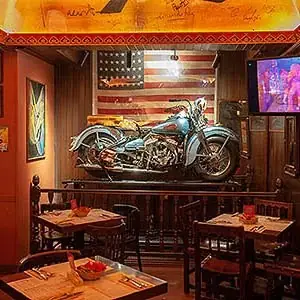Dining area with a vintage motorcycle mounted on the wall in front of a large American flag