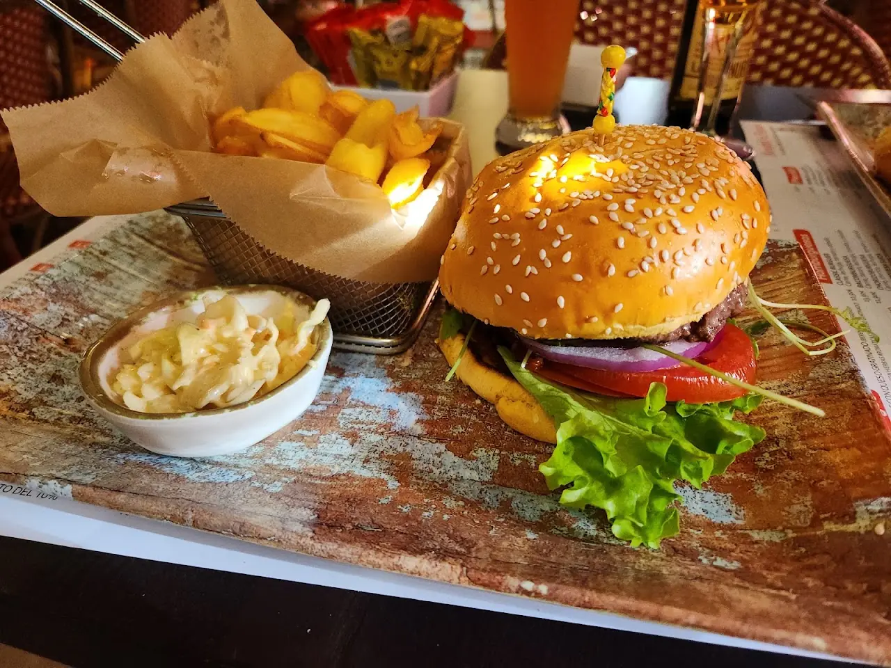 A cheeseburger with lettuce and tomato served in a basket alongside fries.