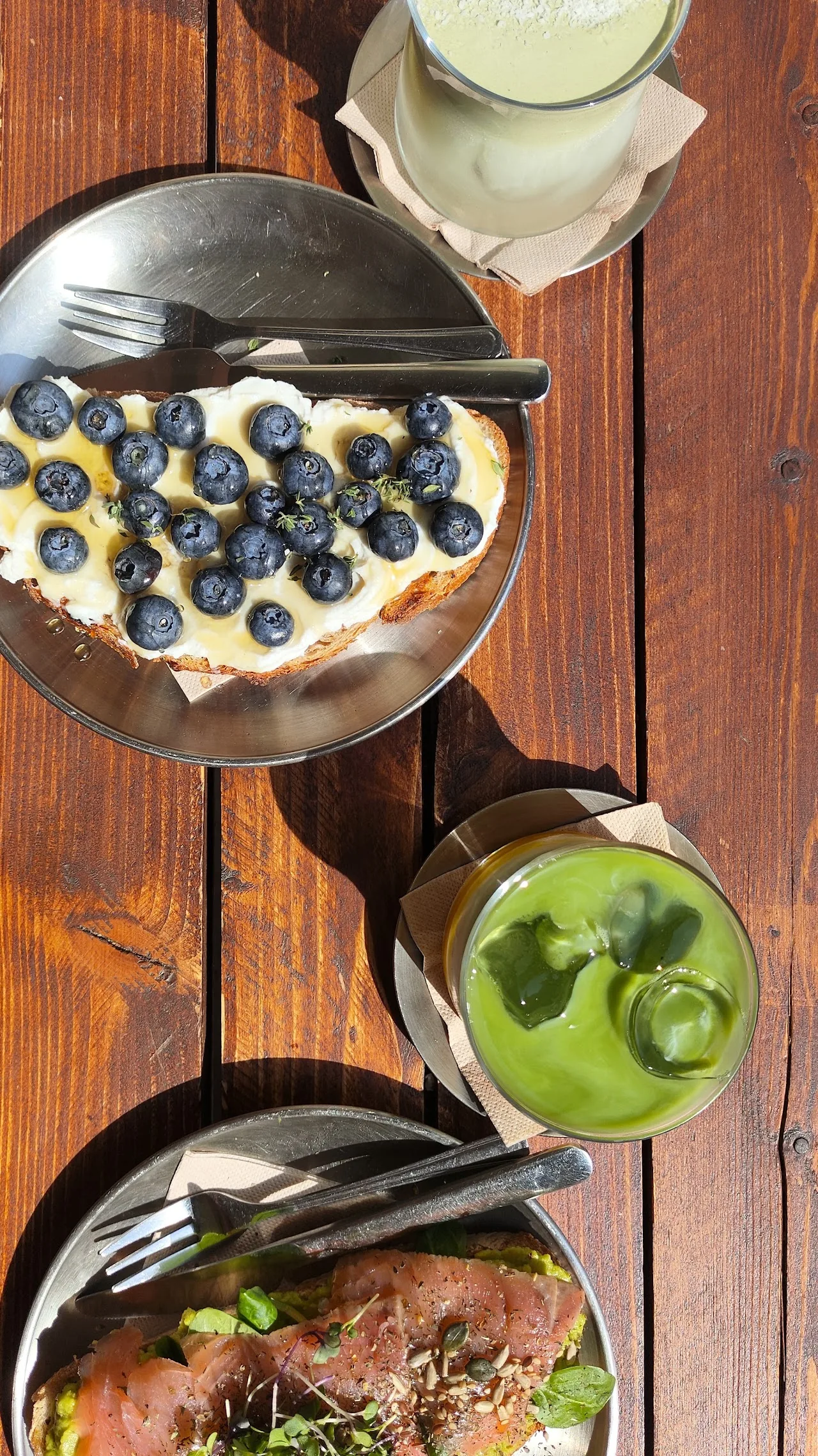 Overhead view of a yogurt bowl topped with blueberries beside a green smoothie