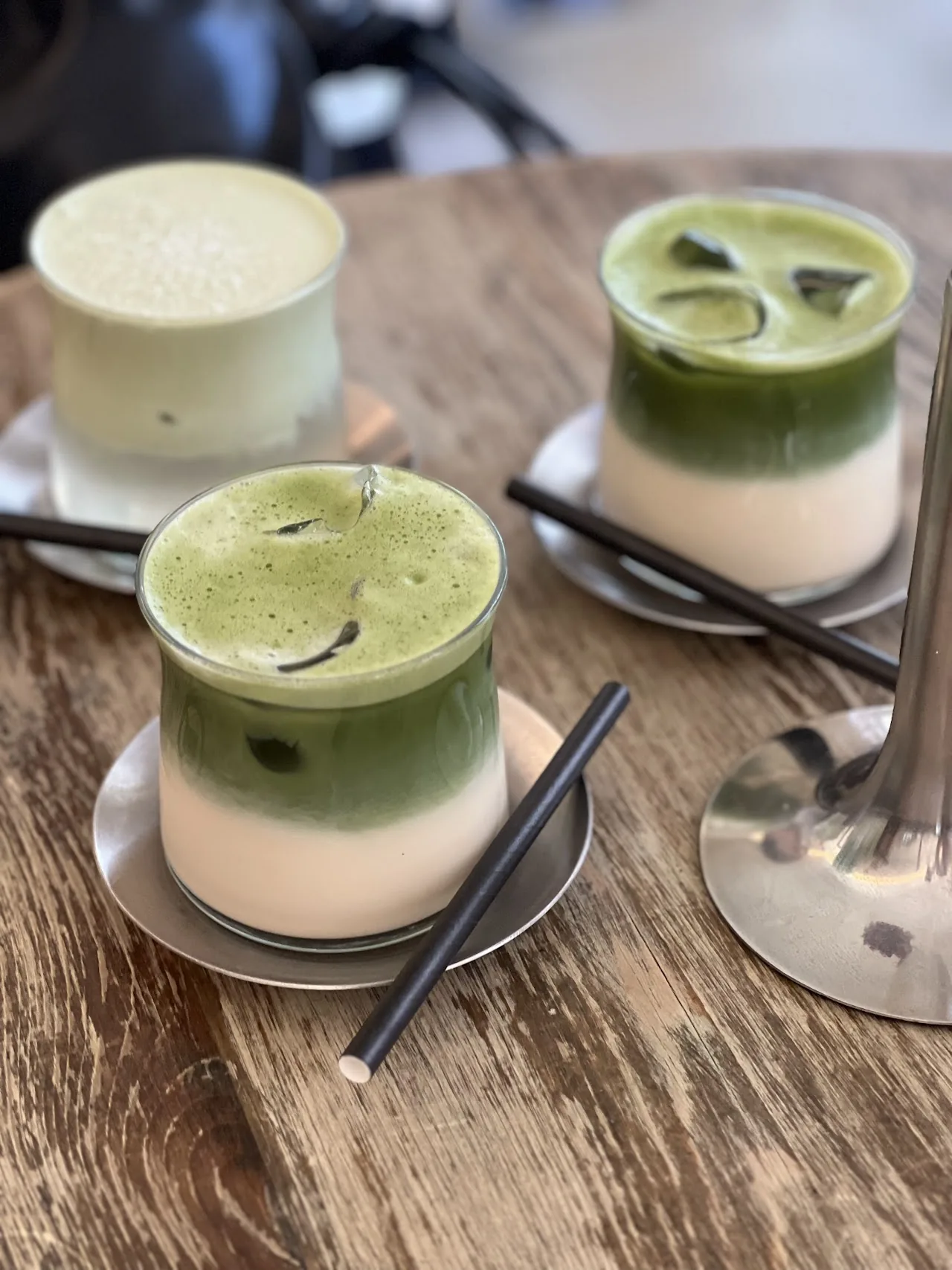 Two matcha lattes layered with cream, served in glass cups