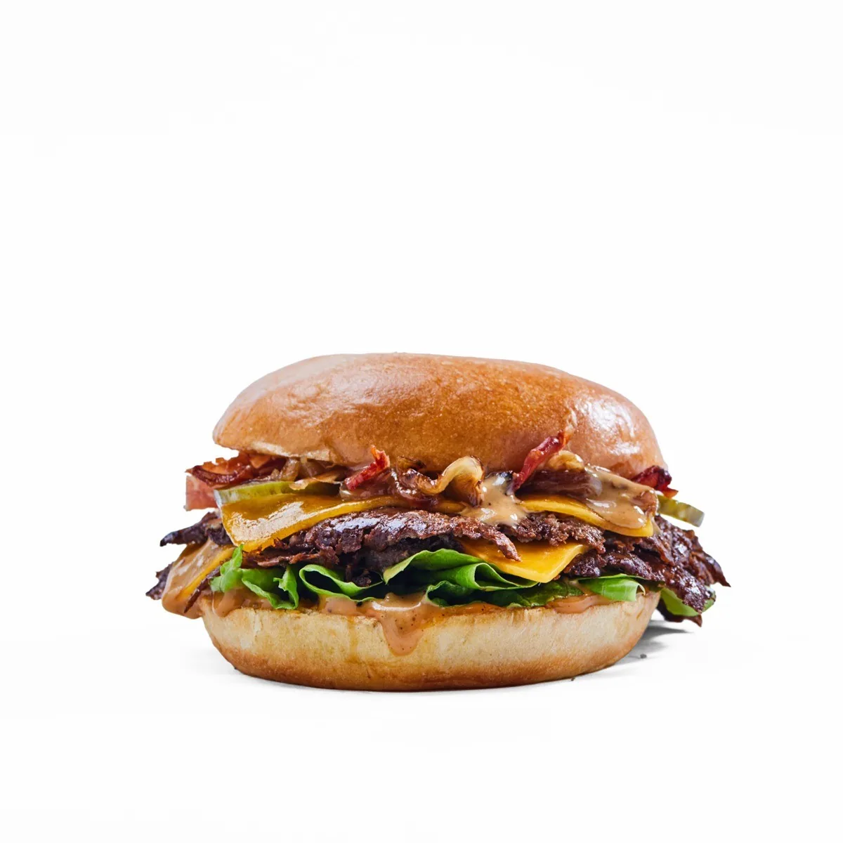 A burger with bacon, cheese and greens on a white background