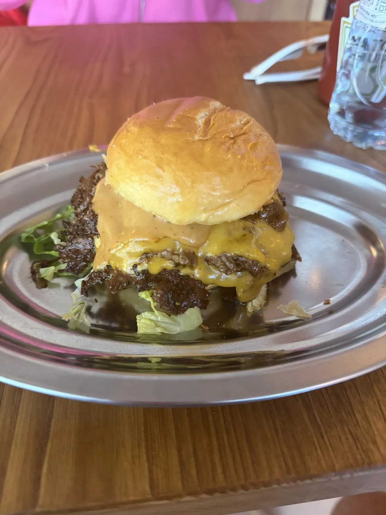 A stacked burger with melted cheese and lettuce on a bun