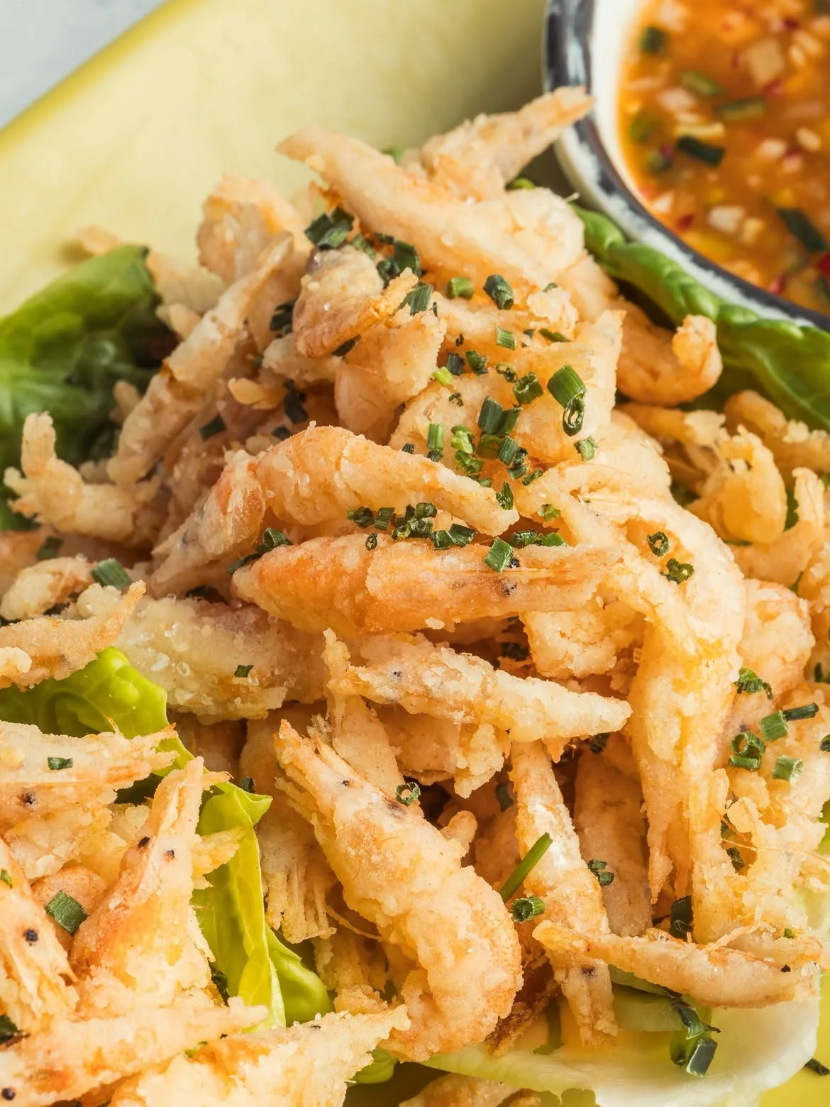 A heap of golden fried small fish with green peppers and chopped herbs