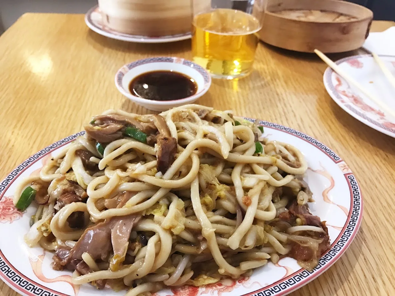 A plate of stir-fried noodles with meat and greens