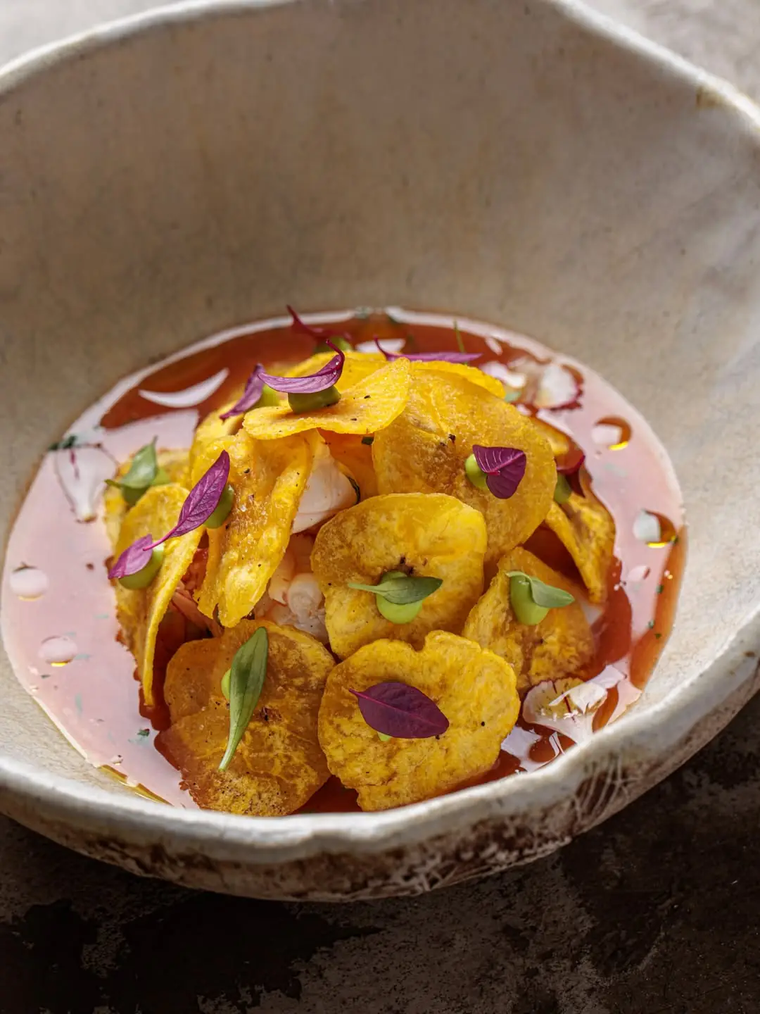 Ceviche topped with fried yellow plantain chips and purple leaves