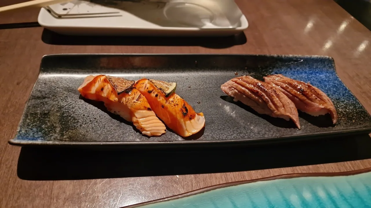 A long dark tray with two rows of nigiri on a wooden table