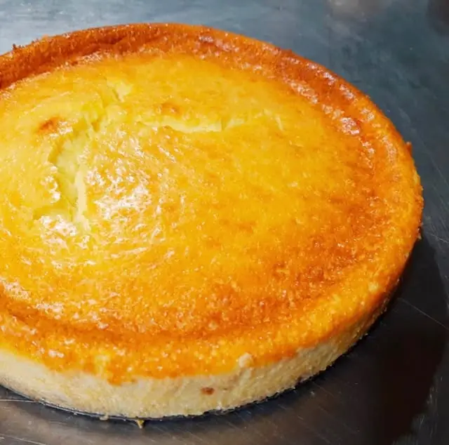 Whole golden-baked Basque-style cheesecake on a metal surface