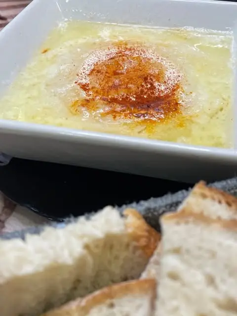 White dish of melted cheese or egg with paprika-spiced oil, served with sliced toasted bread