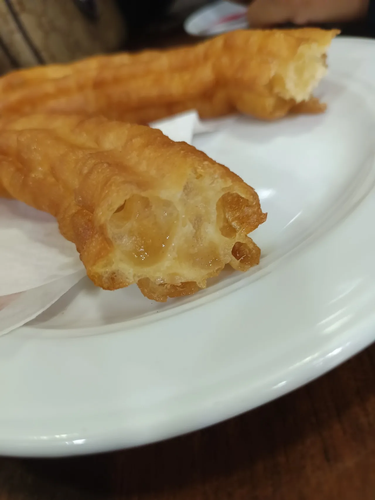 A close view of a golden churro on a white plate
