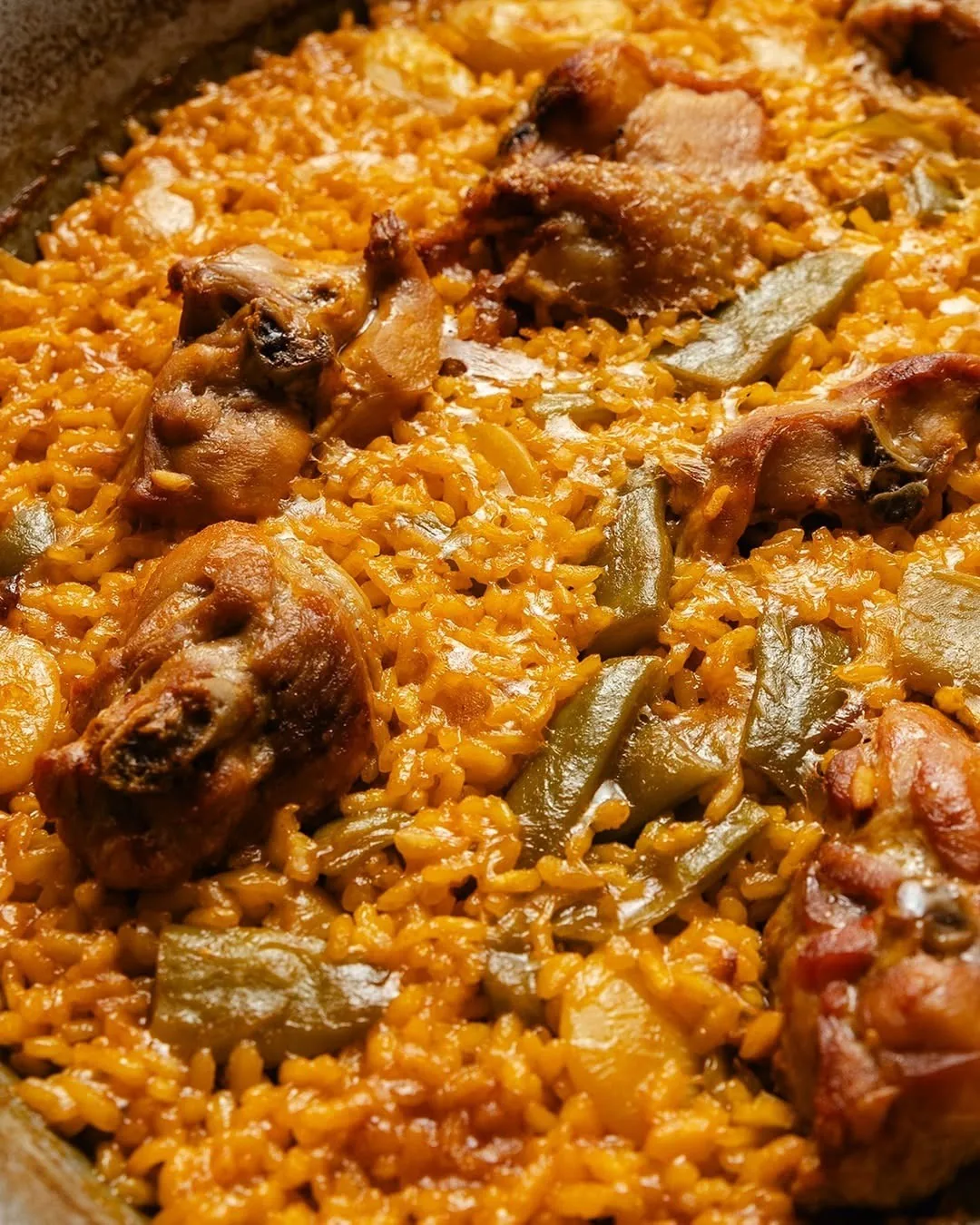 A close-up of rice with pieces of meat and green beans
