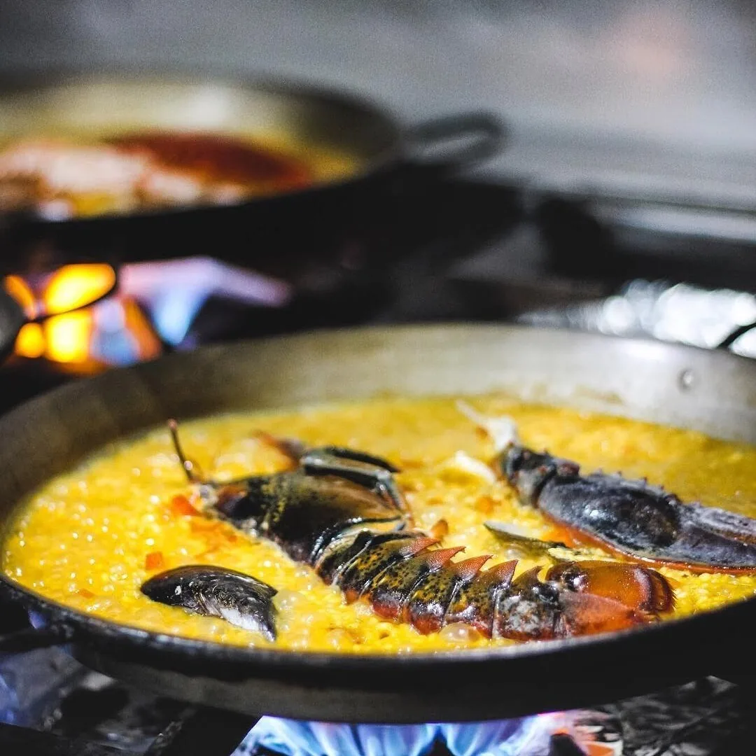 A pan of yellow rice with a dark crustacean over a flame