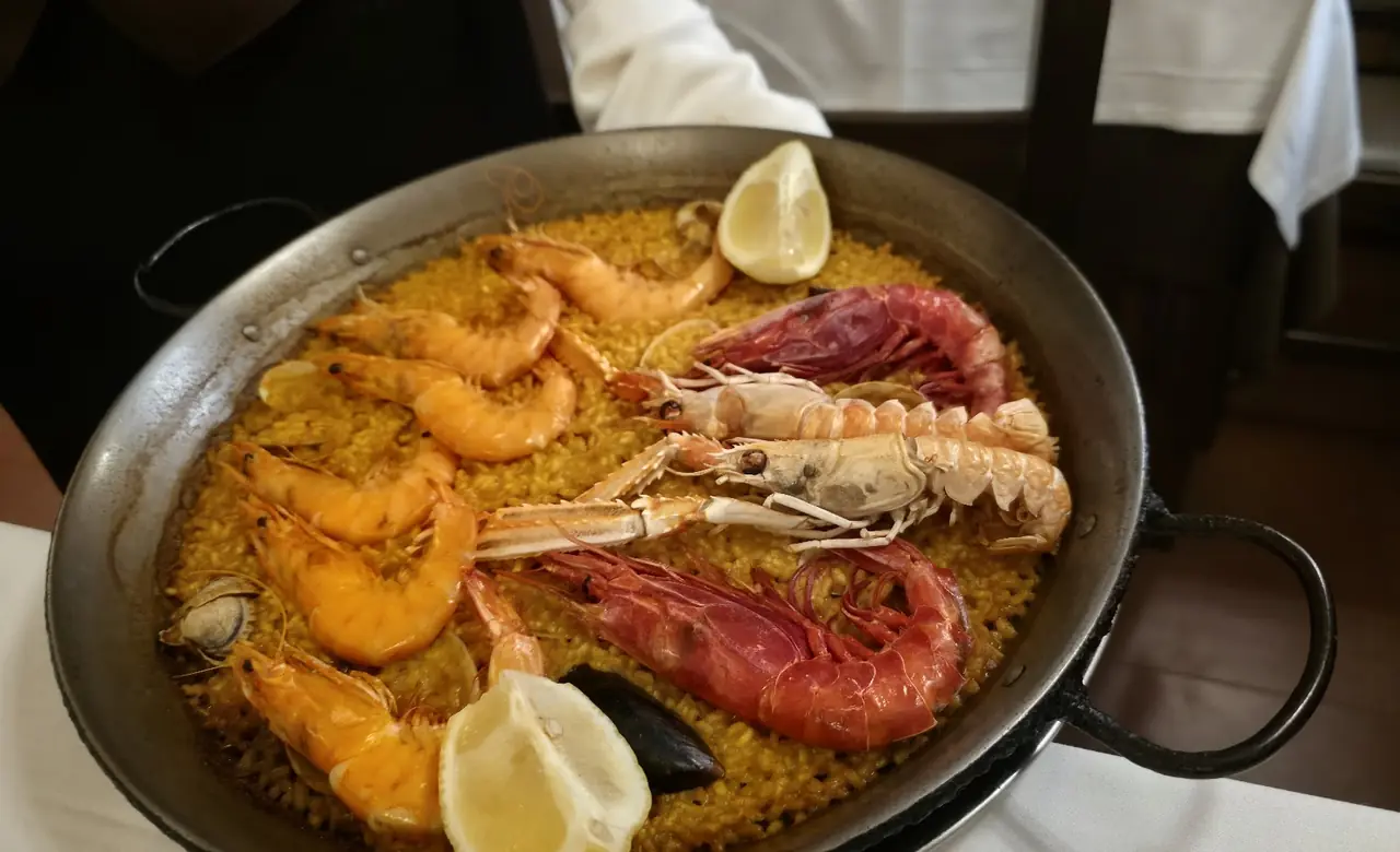 Seafood paella with langoustines, prawns, mussels and lemon wedges in a pan