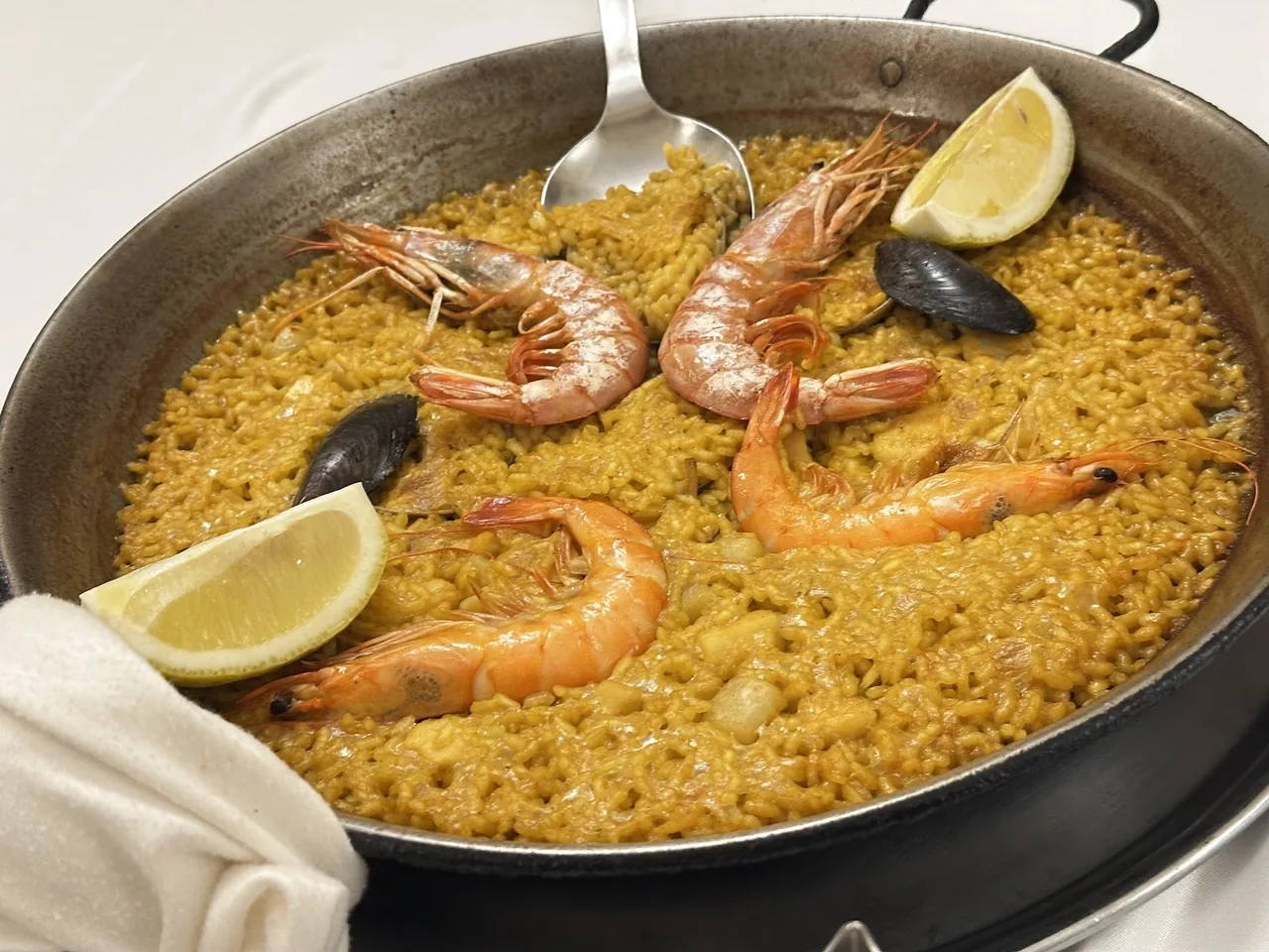 Seafood paella with whole prawns, mussels and a lemon wedge