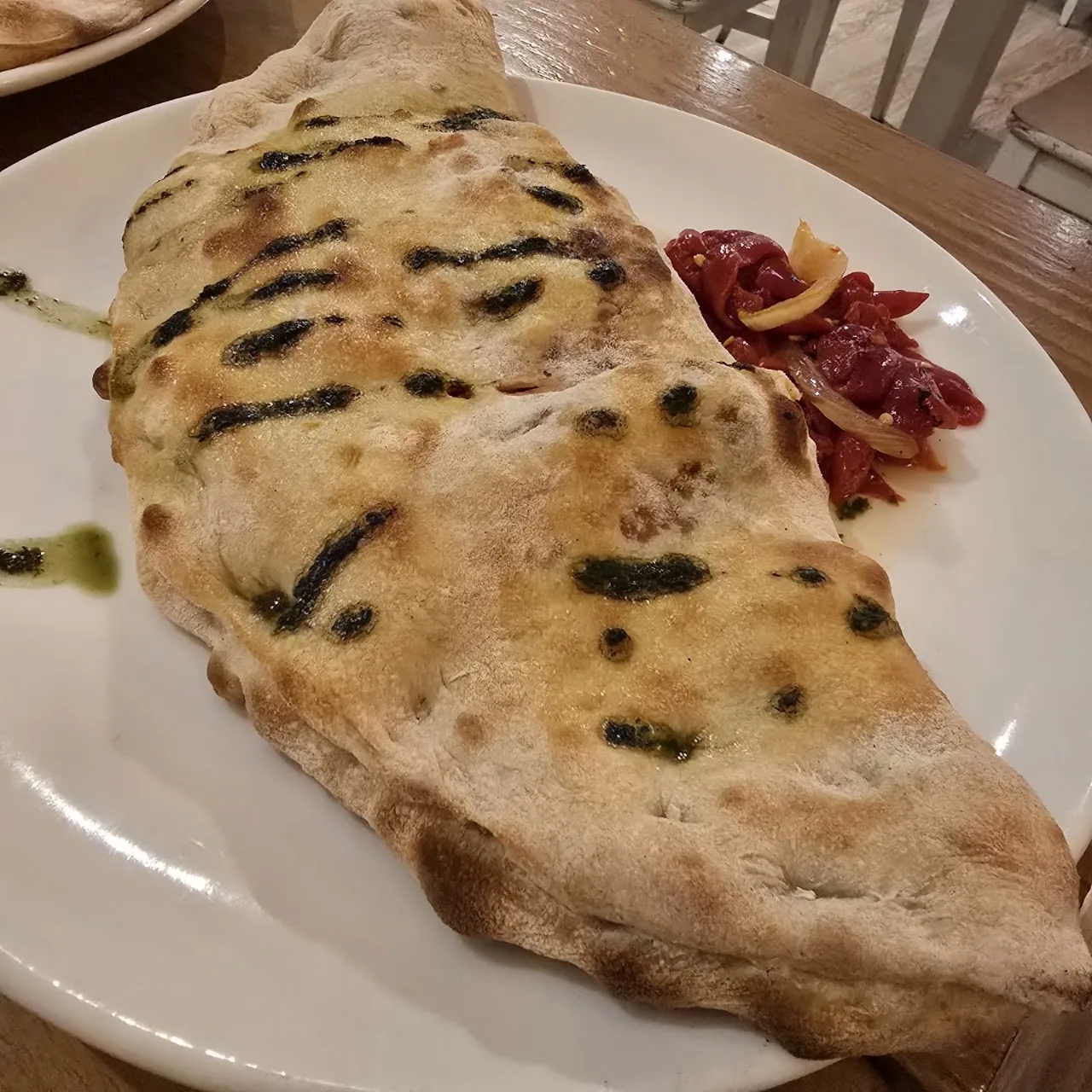 A grilled flatbread topped with cured meat on a plate