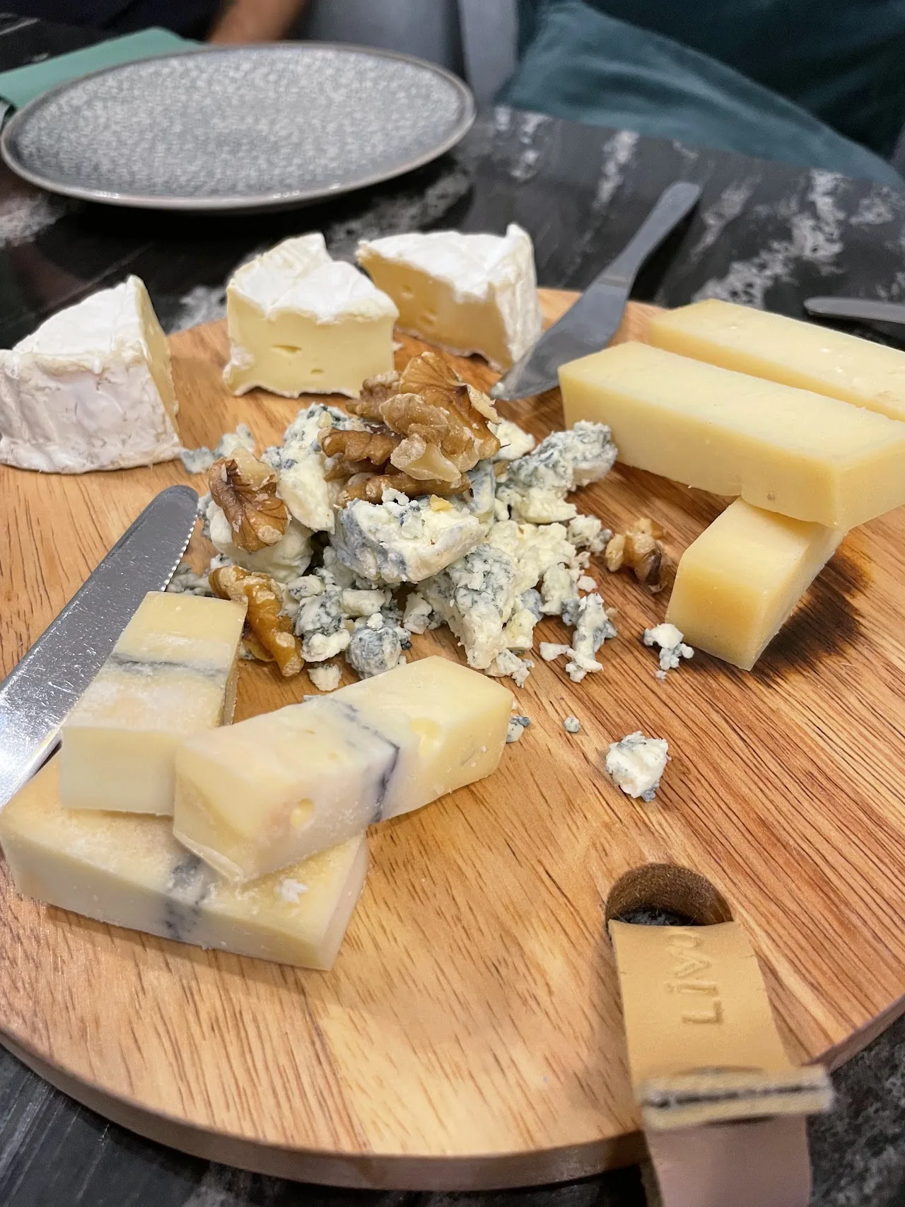 An assortment of cheeses on a wooden board with a knife