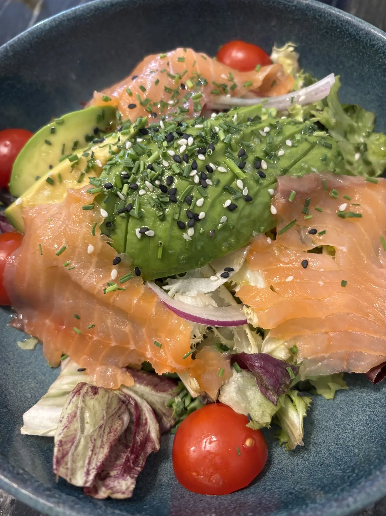 A salad of smoked salmon, avocado, tomato, and greens
